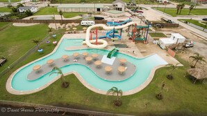 Ein Luftbild eines Wasserparks mit großem Pool, mehreren Rutschen und Liegestühlen.