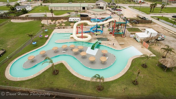 An aerial view of a water park with a large pool, multiple slides, and sun loungers. - Winds of Change - Easy Beach Access (Bolivar Peninsula)