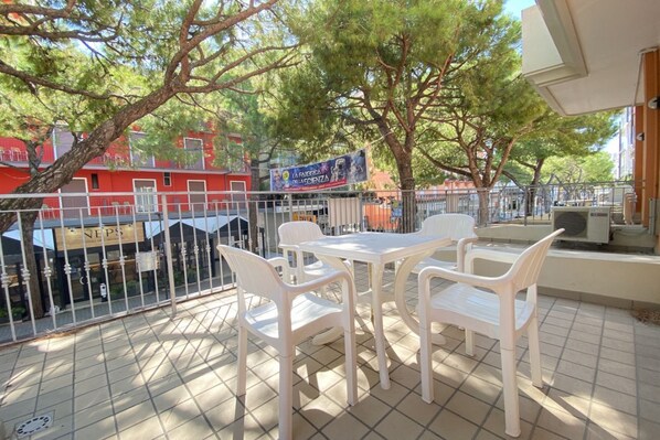 Une terrasse avec une table et des chaises, une vue sur une rivière et, au fond, un bâtiment sur lequel on peut voir une enseigne.