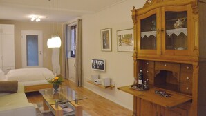 A hotel room with a bed, a glass coffee table, a wooden cabinet, and a television on a shelf.