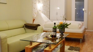 A living room with a glass coffee table, a sofa, a bed, and a wardrobe.