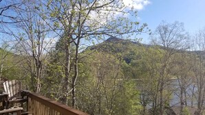 Eine Holzterrasse mit Stühlen mit Blick auf ein bewaldetes Gebiet und ein Gewässer.