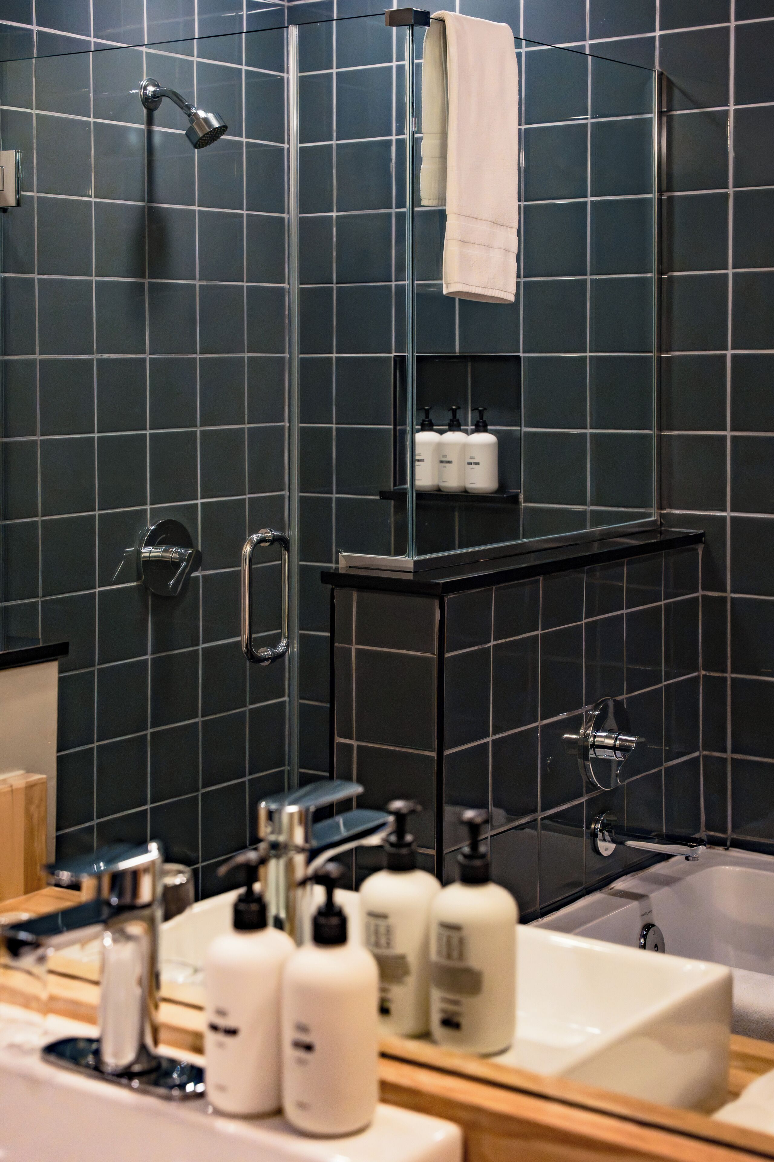 A modern bathroom with a shower, a bathtub, and a vanity with toiletries.