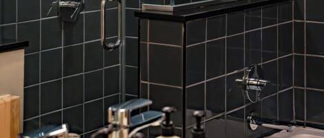 A modern bathroom with a shower, a bathtub, and a vanity with toiletries.