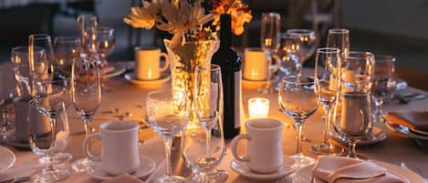 A table set for a meal with wine glasses, plates, and a vase of flowers.