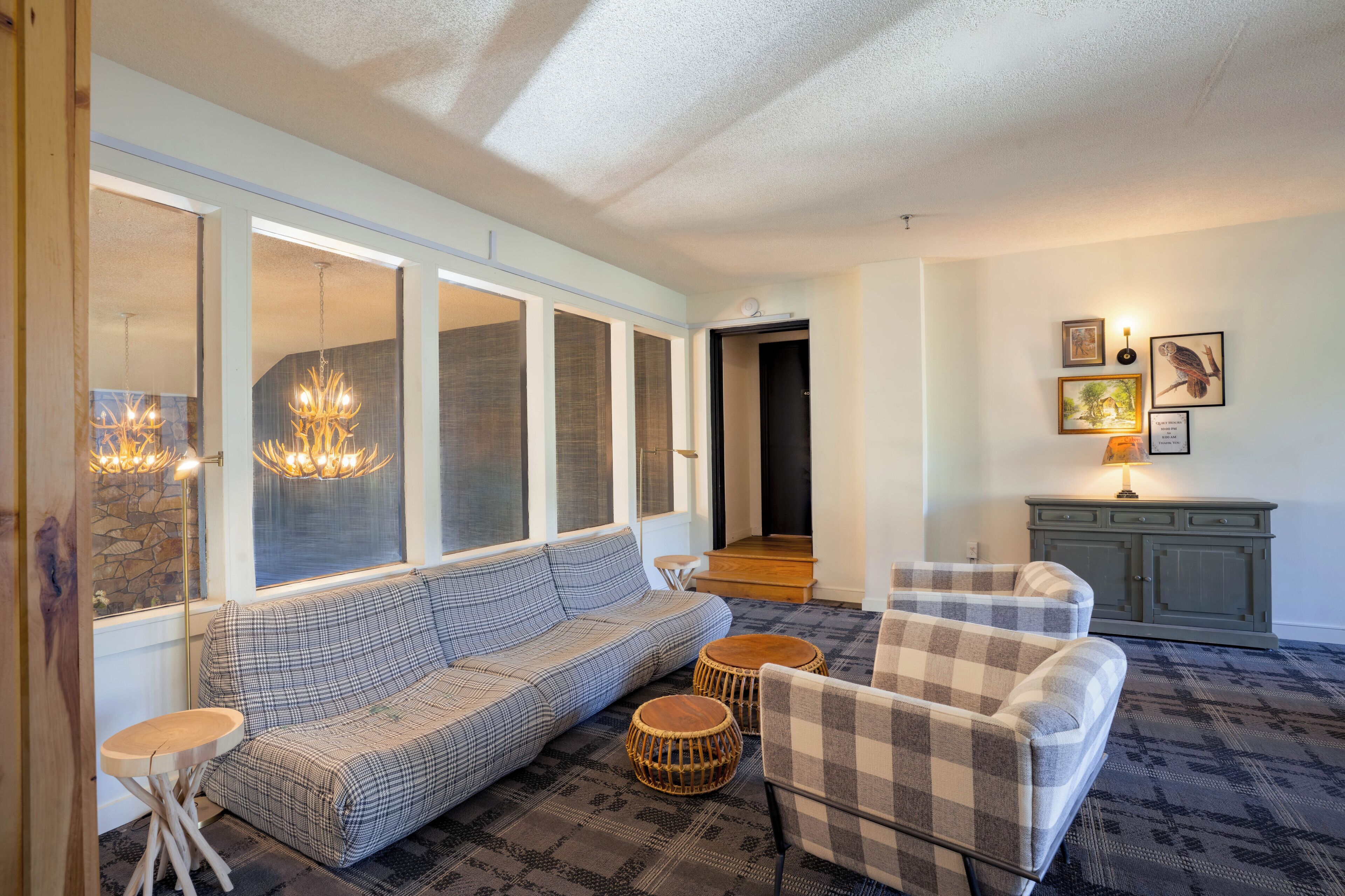 A living room with a sofa, armchairs, a small table, and a lamp.