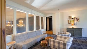 Una sala de estar con sofá, sillones, una mesita y una lámpara.