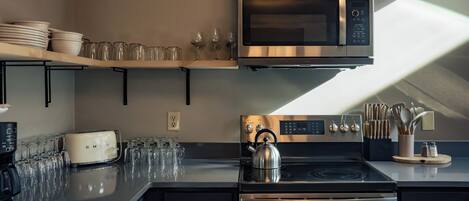 Una cocina moderna con microondas, tostadora, hervidor y horno de acero inoxidable.