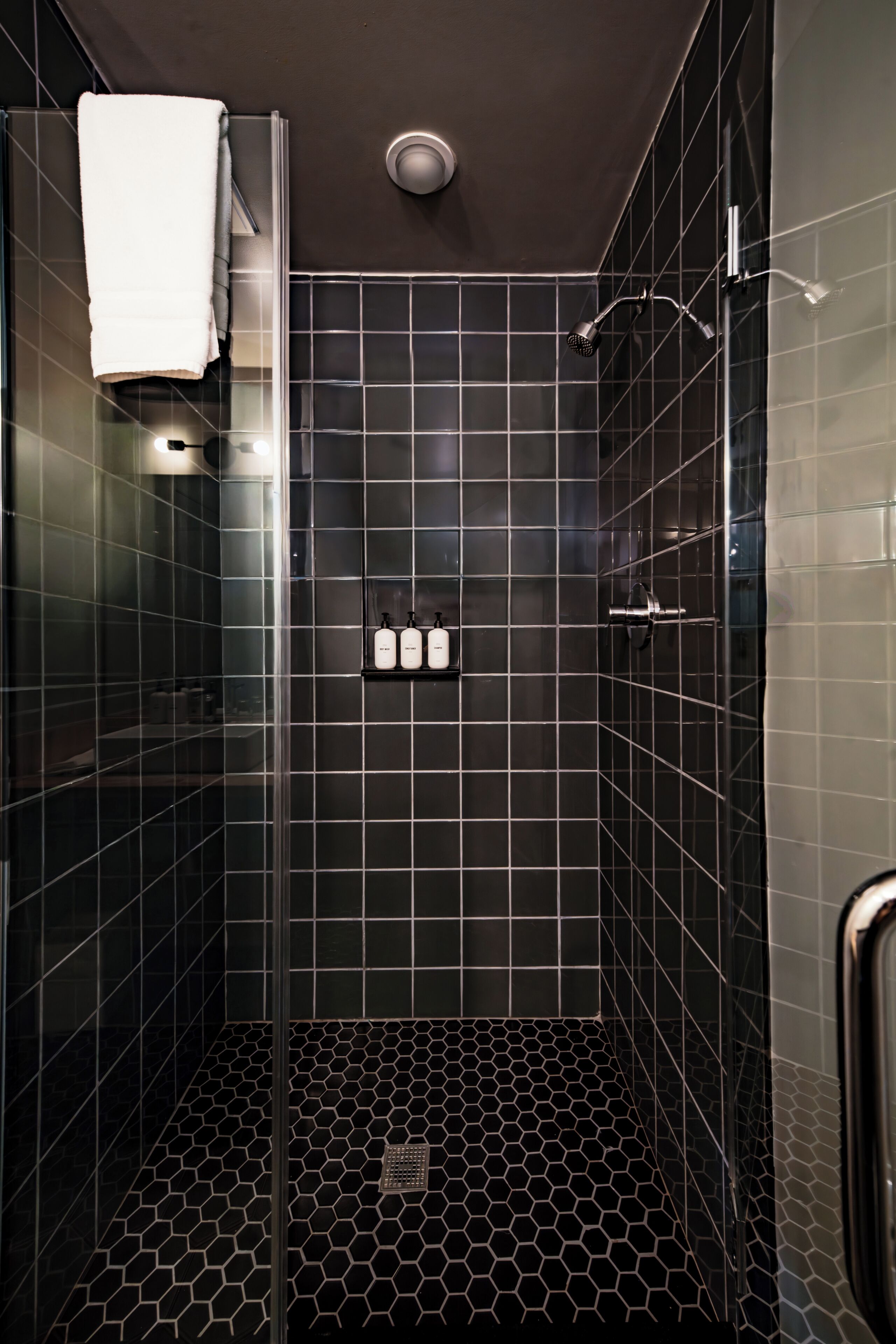 A shower with a glass door, a white towel hanging on the door, and a showerhead.