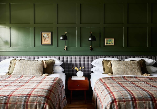 A room with two beds, a nightstand with a vase, and wall-mounted lamps. - Hunter Lodge, a Bluebird by Lark (Hunter)