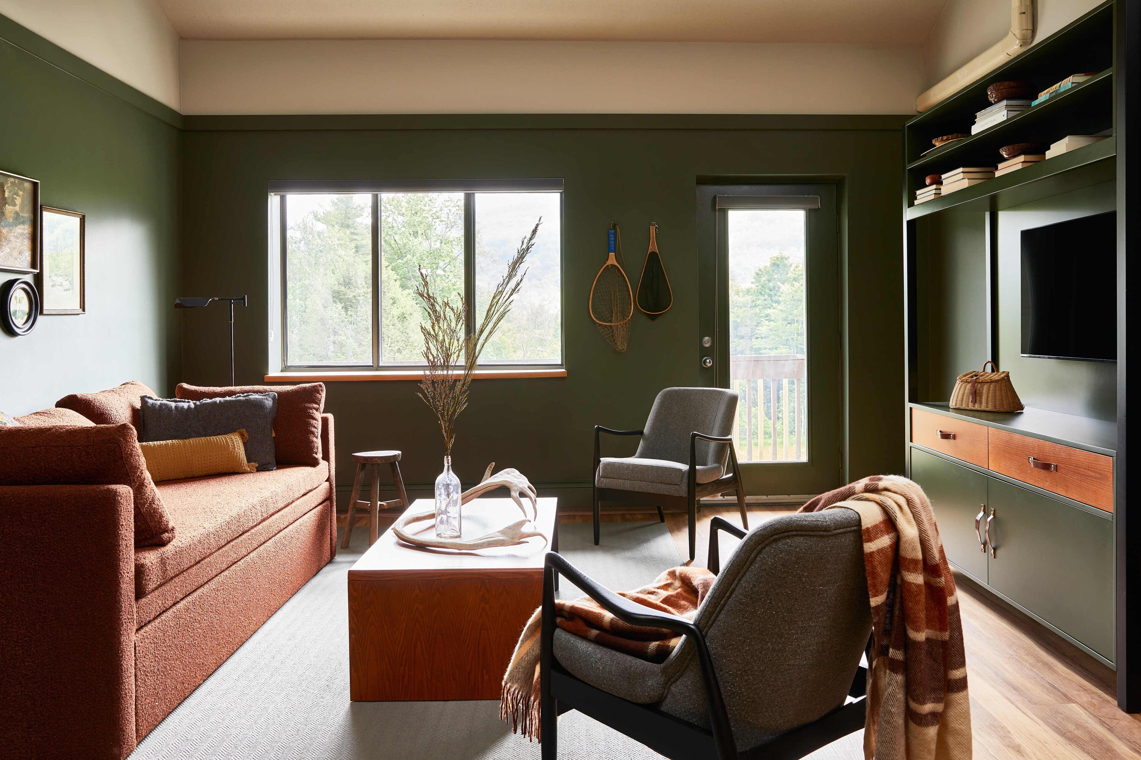 Ein Wohnzimmer mit einer Couch, einem Sessel, einem Couchtisch, einem Fernseher und einem Bücherregal.
