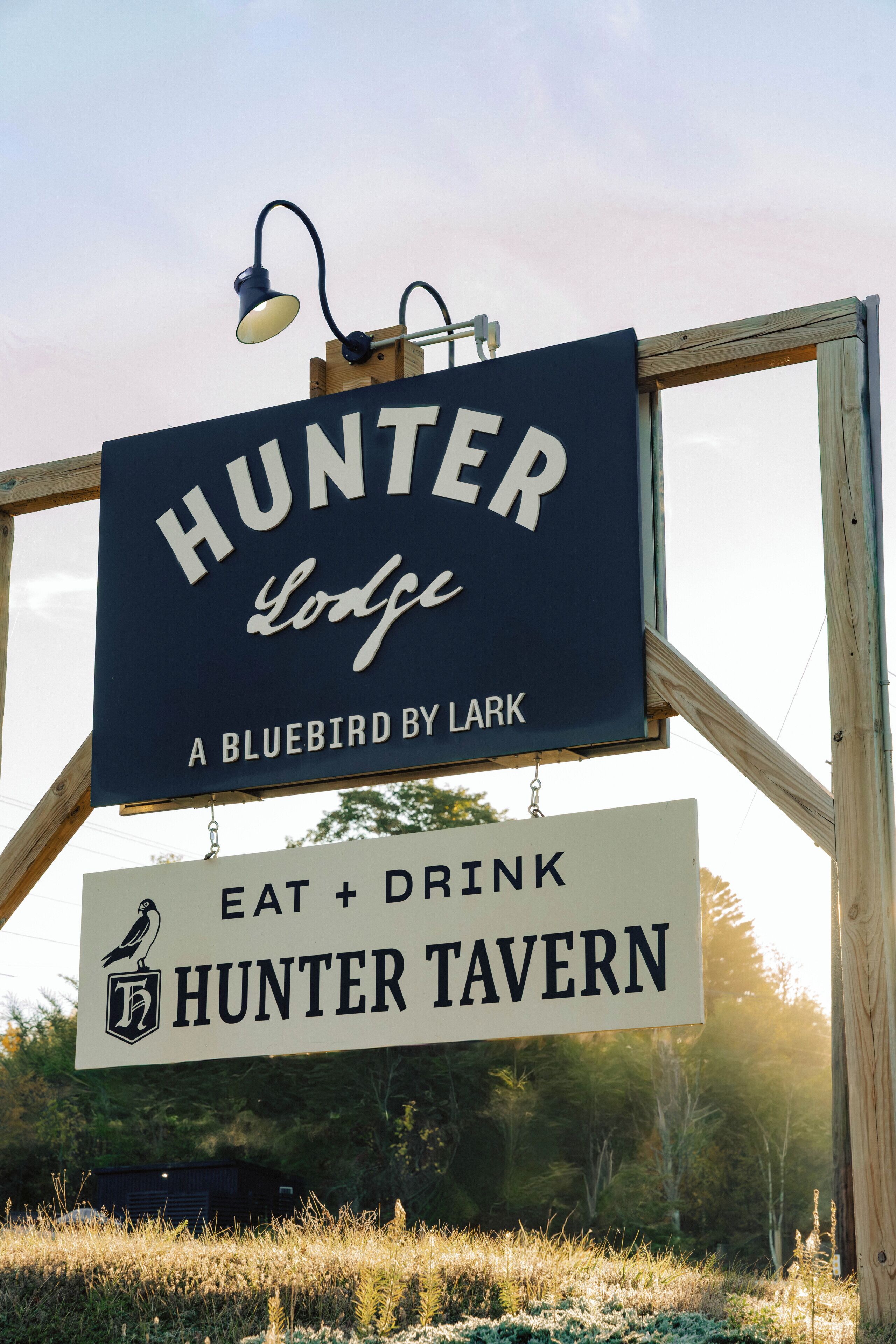 Une enseigne pour le « Hunter Lodge », avec un logo représentant un oiseau et l’inscription « A Bluebird by Lark ».
