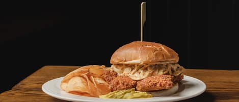A plate with a sandwich, chips, and a side of coleslaw on a wooden table.