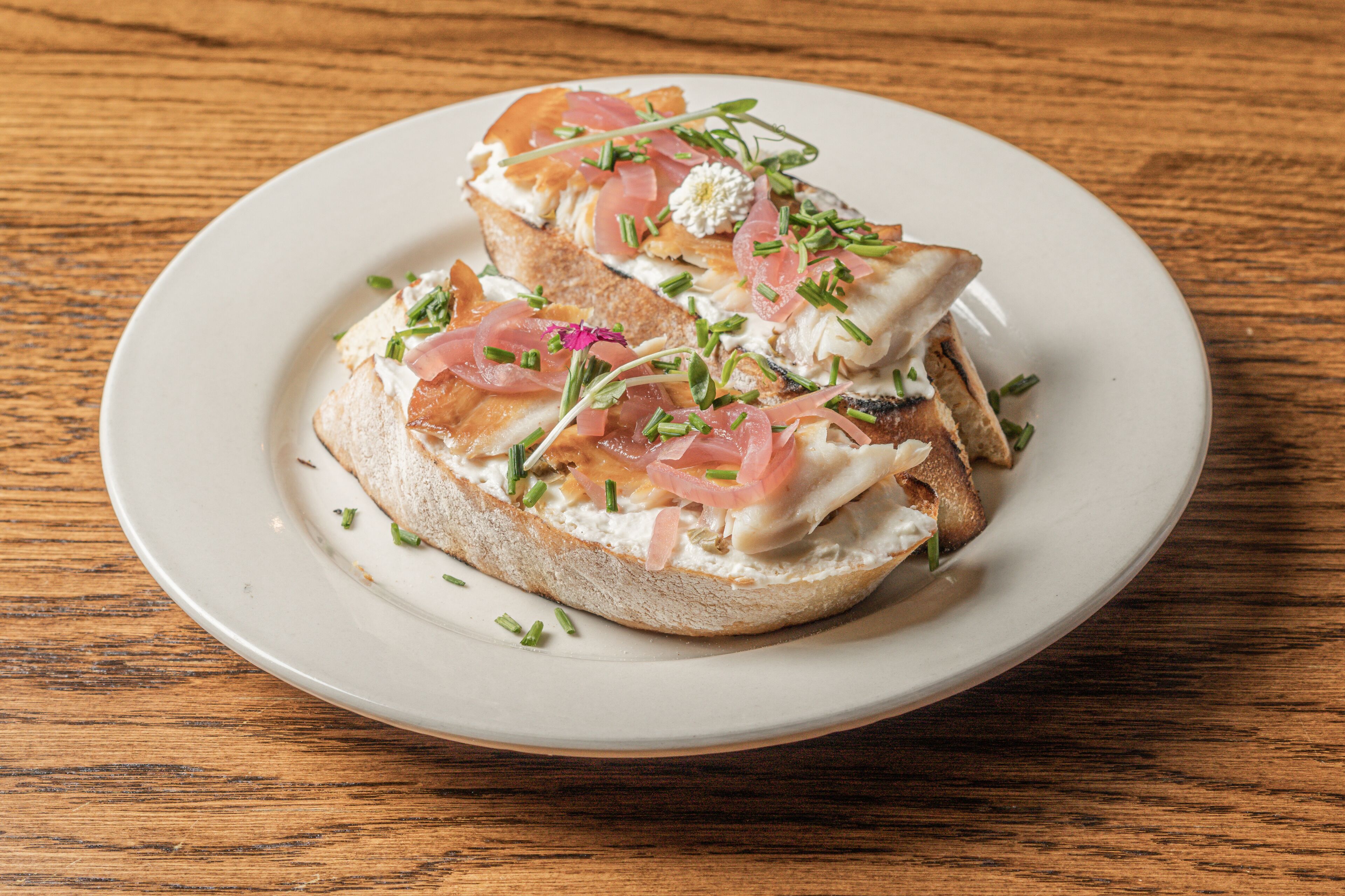 A plate with a sandwich on a wooden table.