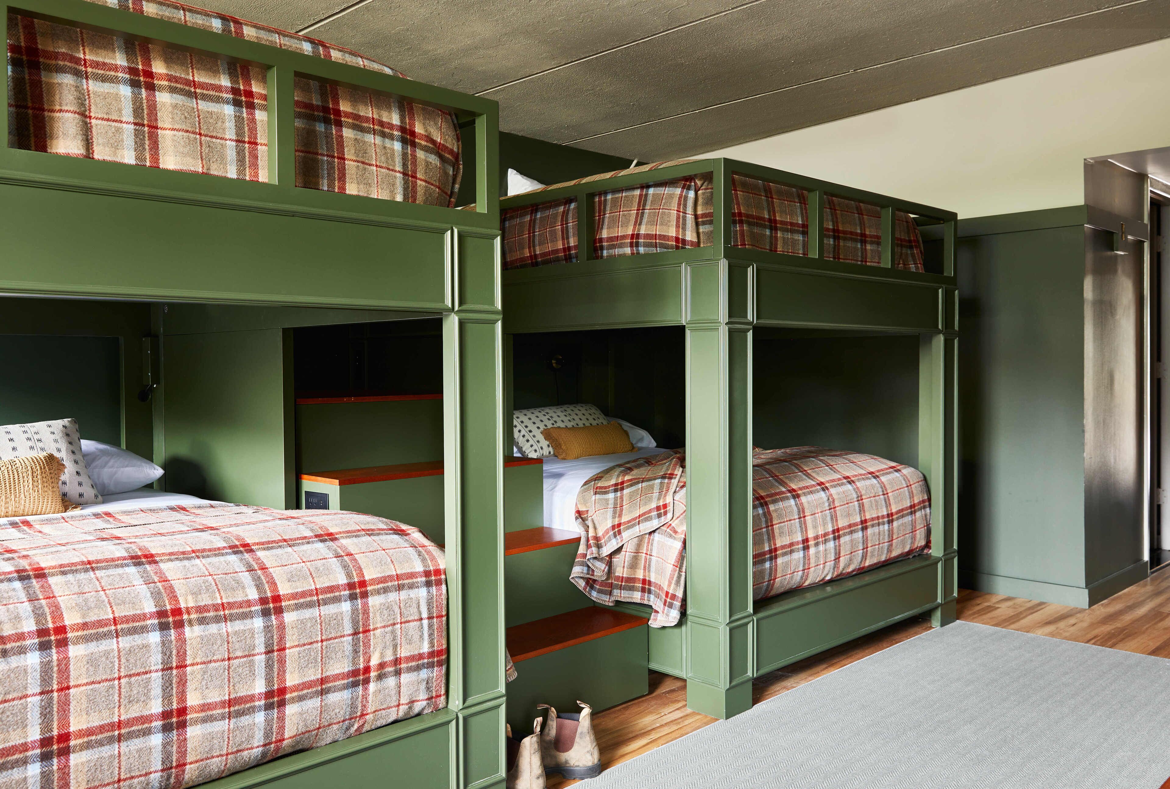 A bunk bed room with green walls and plaid bedding.