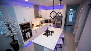 Uma cozinha moderna com armários brancos, uma ilha central e um lustre.