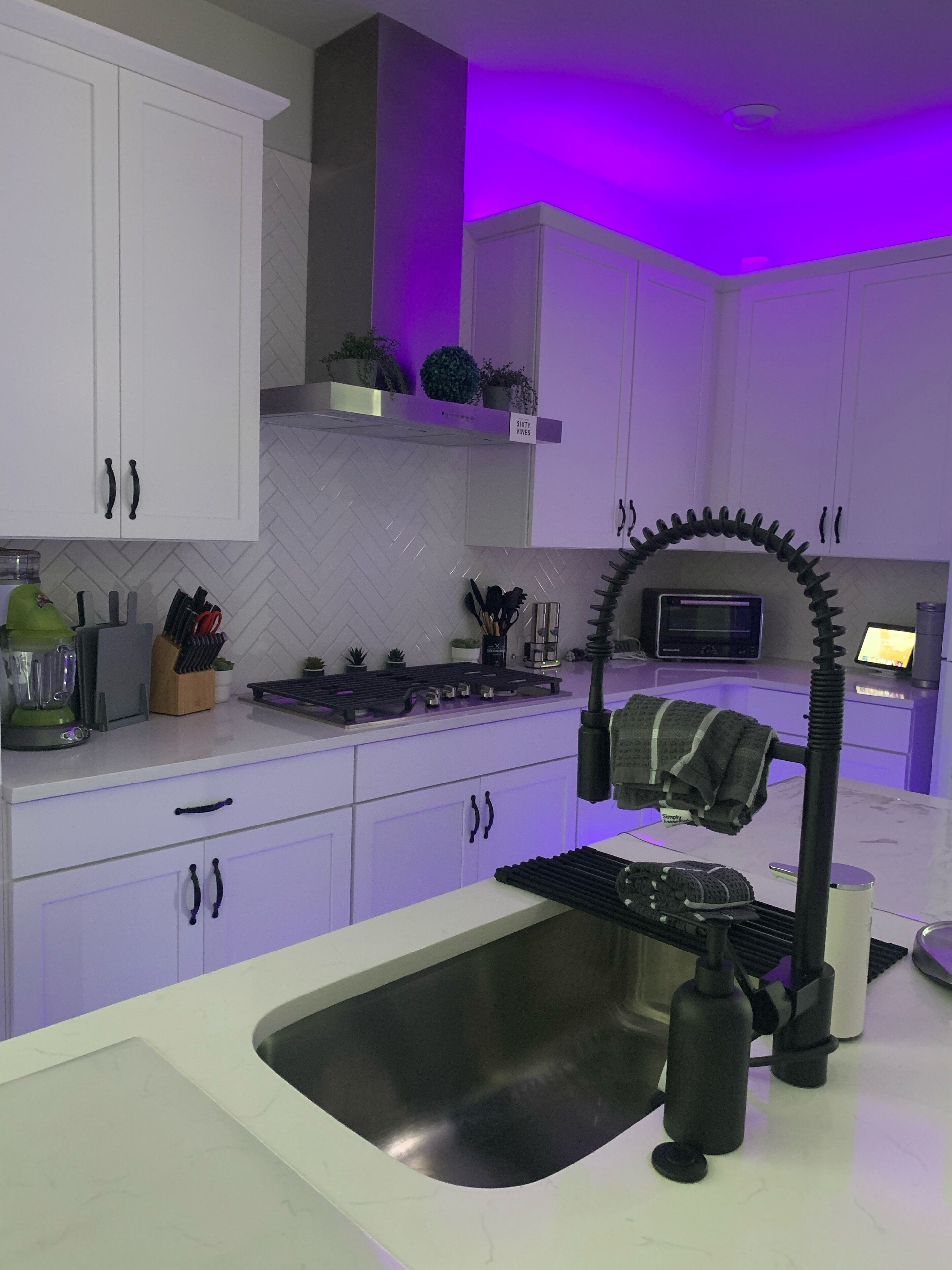 Una cocina moderna con armarios blancos, salpicadero con estampado de espiga y horno empotrado.