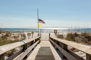 Ein hölzerner Steg führt zu einem Strand mit einer US-amerikanischen Flagge und einer gelben Flagge.