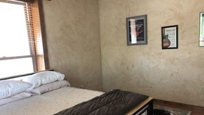 Ein Schlafzimmer mit einem Bett, einem Hund und zwei gerahmten Bildern an der Wand.