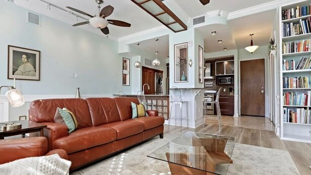 A spacious living room with a leather sofa, a glass coffee table, and a bookshelf filled with books. - Heart of downtown (St. Petersburg)