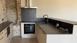 Een compacte keuken met een inbouwoven, een roestvrijstalen afzuigkap en een moderne gootsteen.