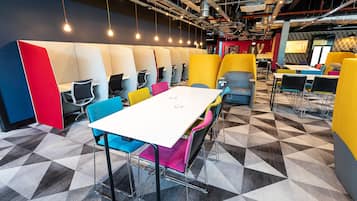A modern meeting room with a white table, colorful chairs, and a geometric patterned floor.