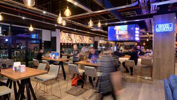 A modern bar area with hanging light fixtures, a neon sign, and a bar counter.