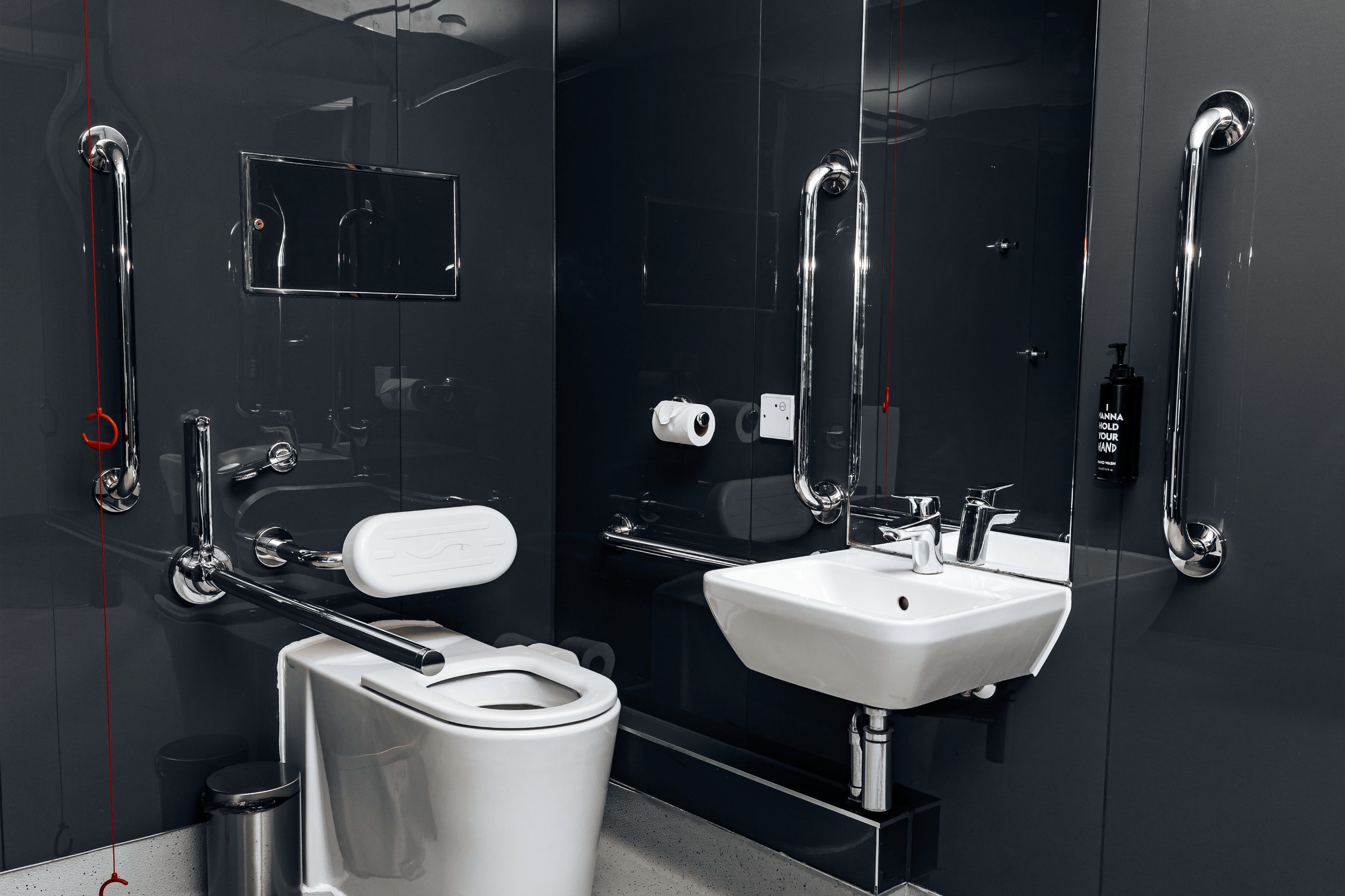 Un baño moderno con inodoro, bidé, lavamanos y secamanos.