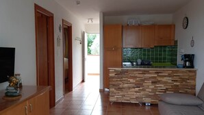 A modern kitchen with wooden cabinets, a built-in island, and a green tiled backsplash.