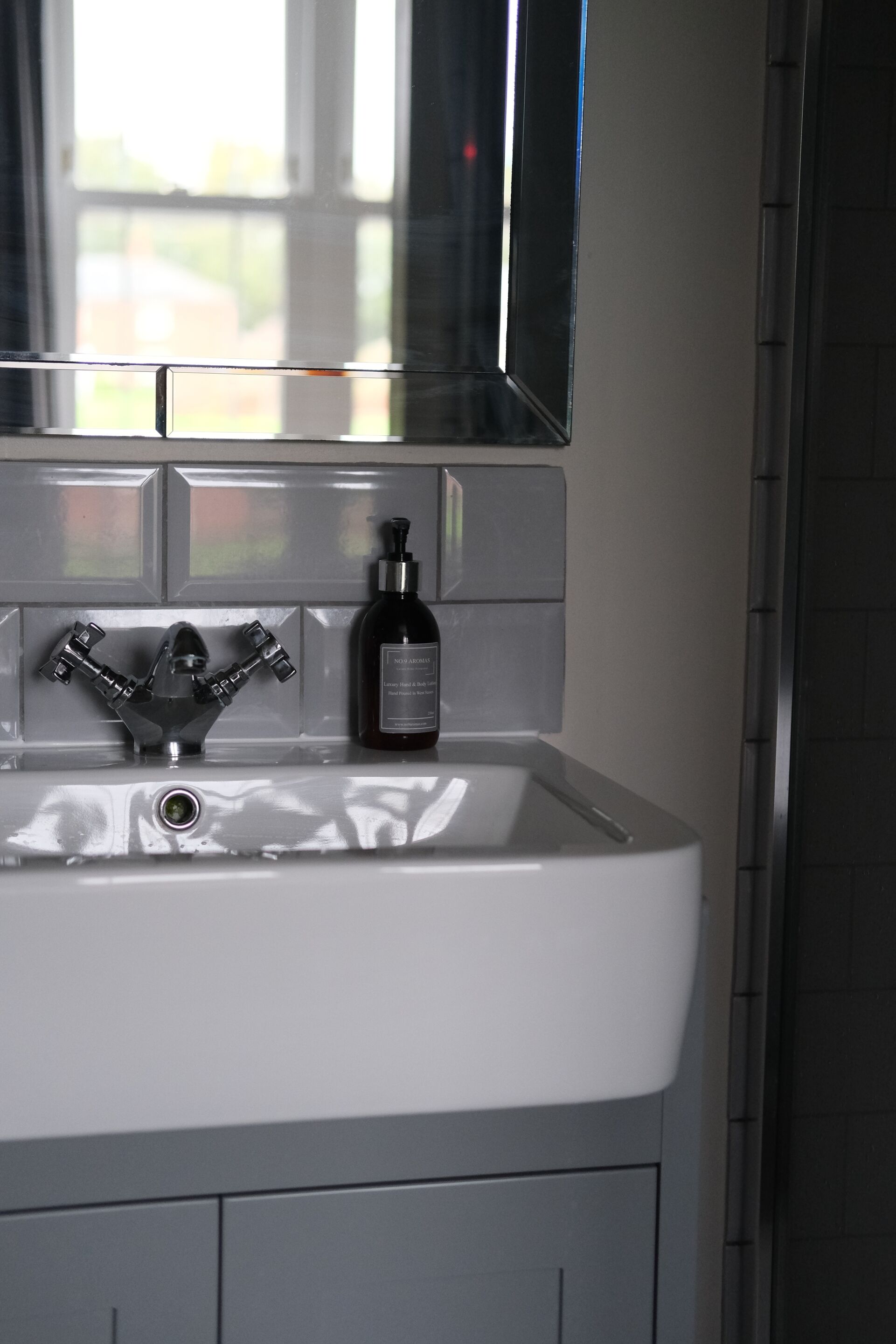 A bathroom with a white sink, a mirror above it, and a bottle of hand soap on the sink.