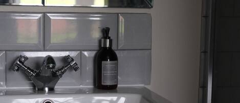 A bathroom with a white sink, a mirror above it, and a bottle of hand soap on the sink.