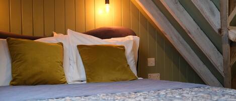 A bed with a patterned bedspread, two pillows, and a wall-mounted light fixture.