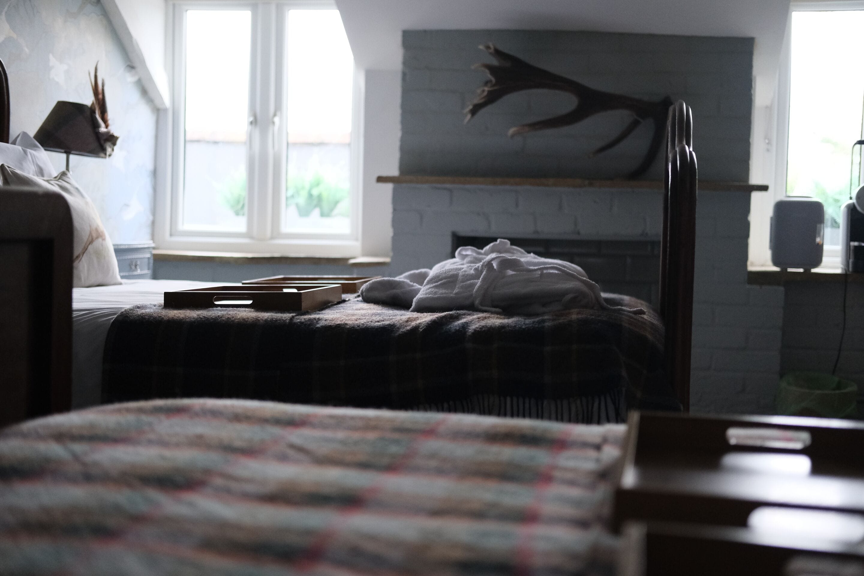 Un dormitorio con cama, chimenea, ventana y lámpara.