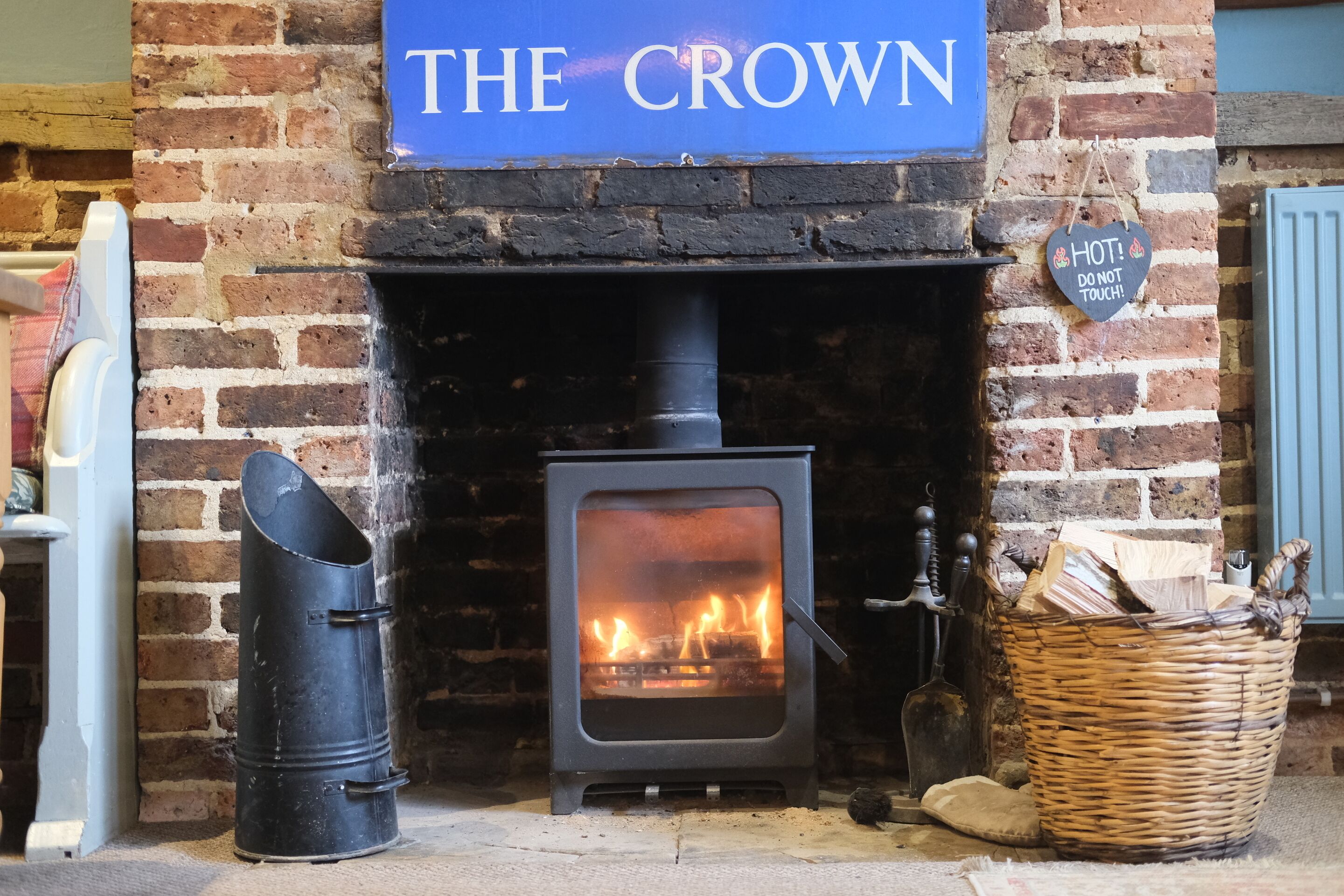 Una estufa de leña frente a una pared de ladrillo con un letrero que dice "THE CROWN".