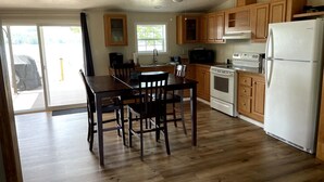 A kitchen with wooden cabinets, a white refrigerator, a stove, and a dining table with chairs. - Sunrise, Sunset, Relax, Repeat Lamoka Cove (Bradford)