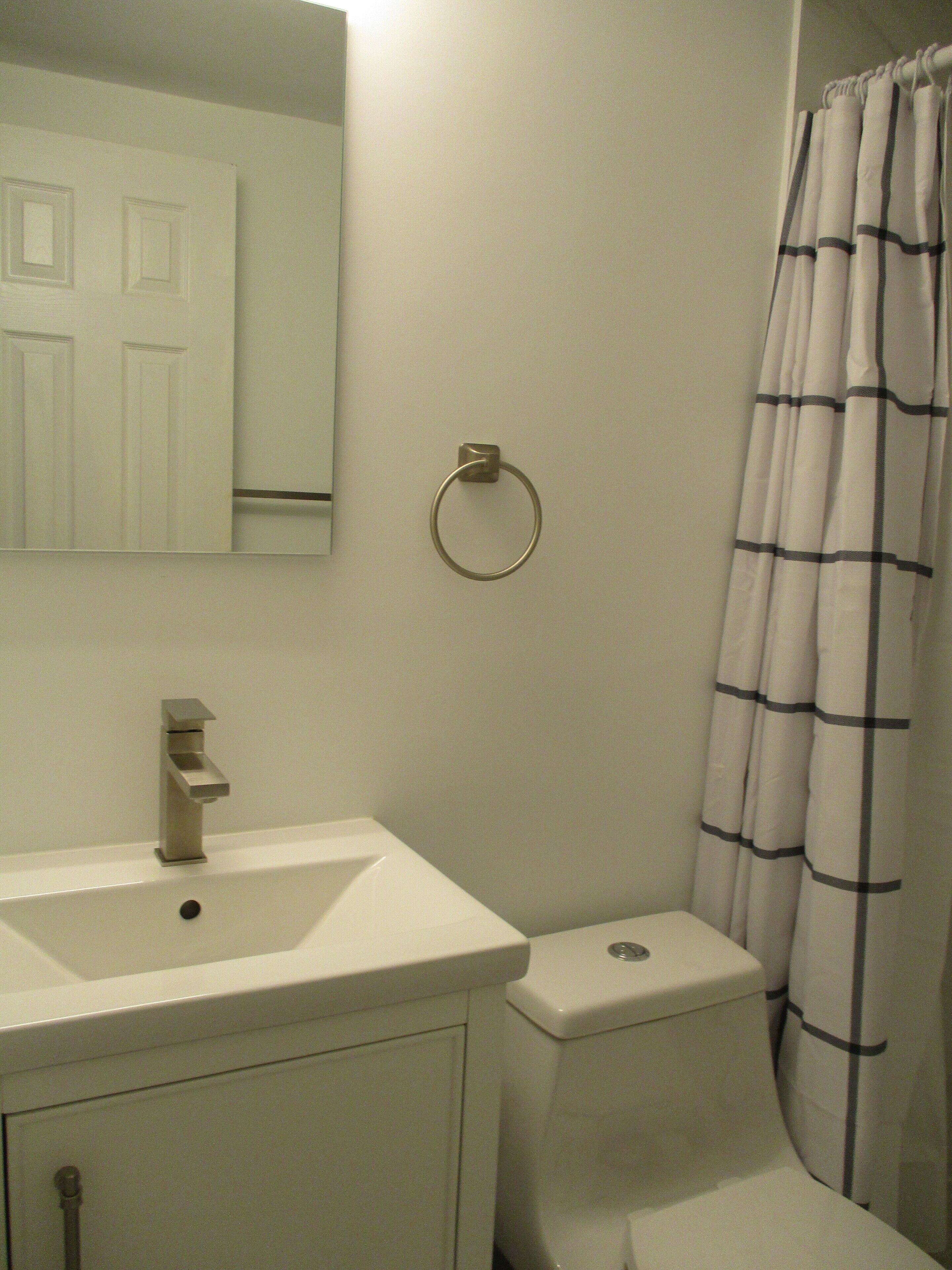 A bathroom with a white sink, a mirror, a toilet, and a shower curtain.