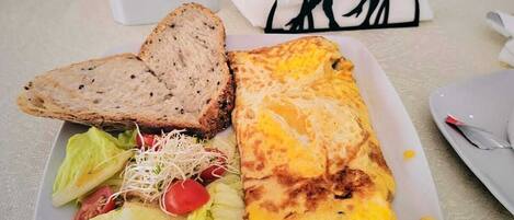 Un plato con tortilla, pan y ensalada.