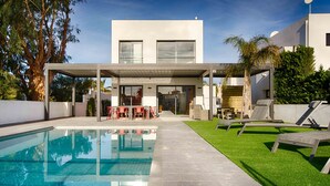 Une maison moderne dotée d’une piscine, d’un espace salon extérieur et d’un patio couvert.