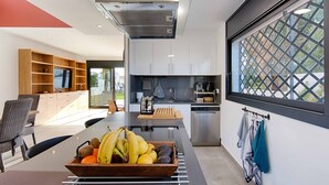 A modern kitchen with a central island, built-in appliances, and a large window with a view. - TER MARAVILLOSA VILLA CANAL TER,PISCINA,WIFI, PARKING (Empuriabrava)