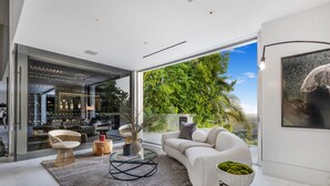 Ein modernes Wohnzimmer mit einer Couch, Sesseln, einem Couchtisch und Blick auf Grün.