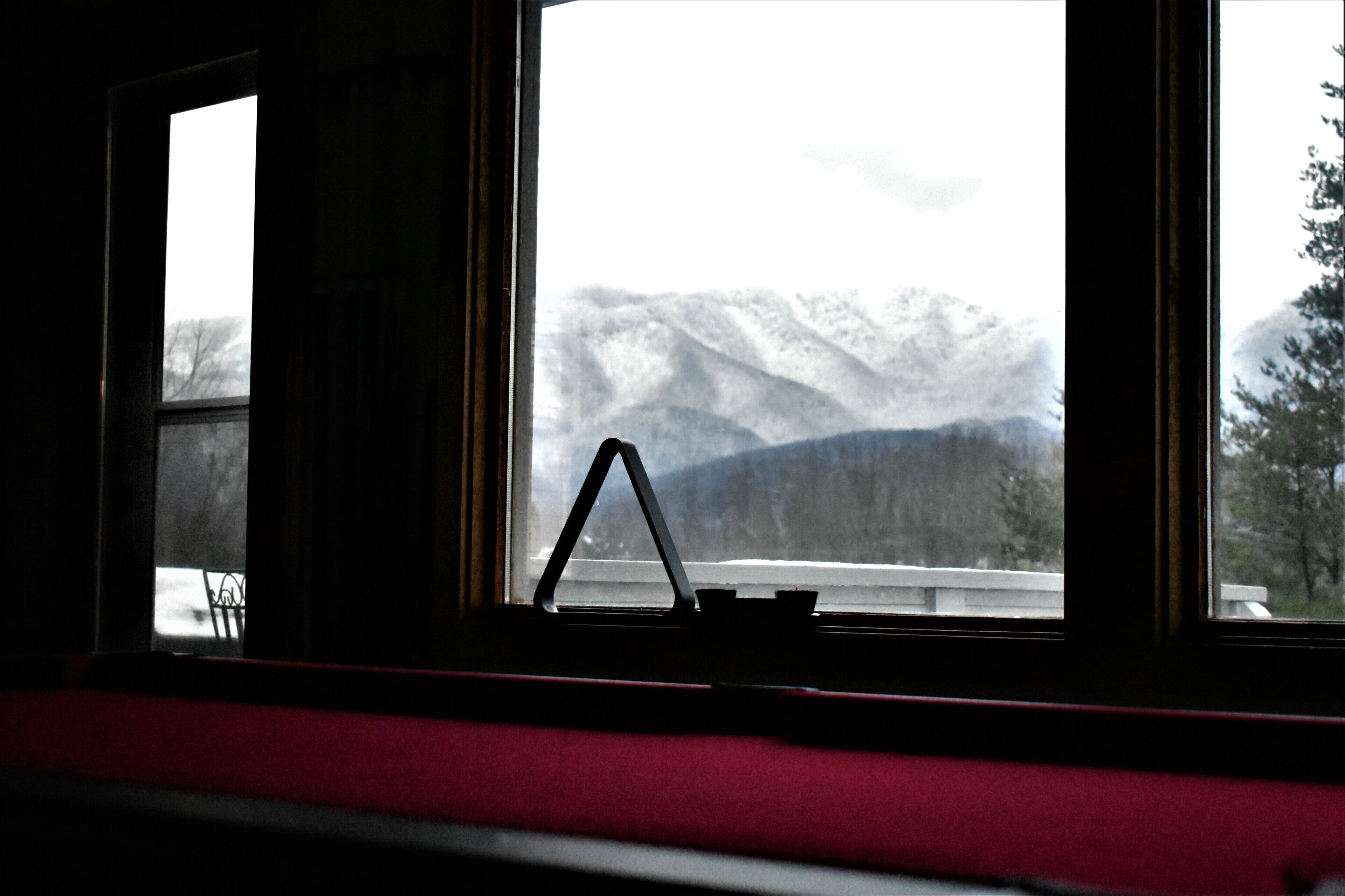 Ein Zimmer mit Blick auf schneebedeckte Berge durch ein Fenster.