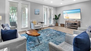 A living room with a large flat-screen TV, a ceiling fan, and a blue patterned rug. - Spacious two bedroom, 2 1/2 bath townhome with sleeping loft (Santa Rosa Beach)