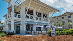 A two-story building with a sign for 'Shunk Gulley Oyster Bar' and 'Chapel at Crosspoint'. There are outdoor tables and chairs under umbrellas. - Spacious two bedroom, 2 1/2 bath townhome with sleeping loft (Santa Rosa Beach)