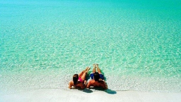 Una pareja descansando en una playa con aguas turquesas cristalinas.