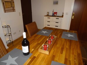 A dining table with star placemats, a bottle of wine, and red candle glasses. - Ferienhaus Urlaub am Meer (Maasholm)