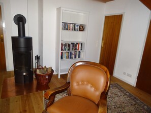A living room with a fireplace, a bookshelf, a leather chair, and a wooden floor. - Ferienhaus Urlaub am Meer (Maasholm)