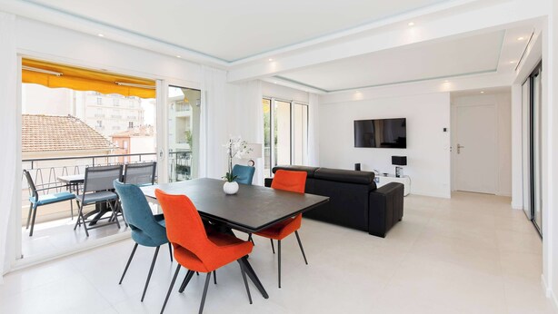 A modern living room with a dining area, a sofa, and a TV.