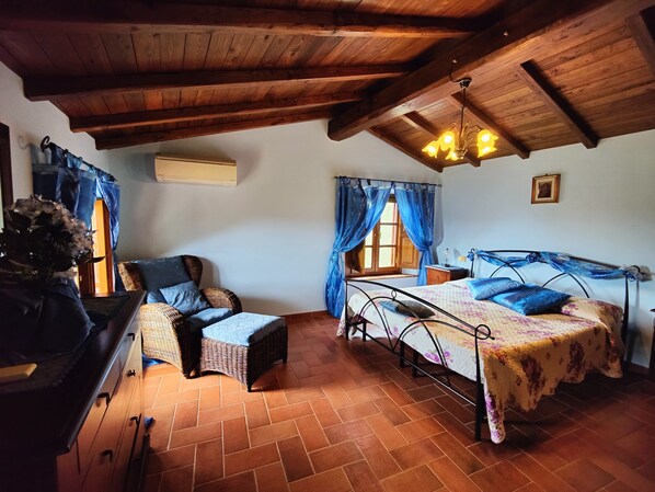 A cozy room with a bed, a chair, a dresser, and a window with curtains.