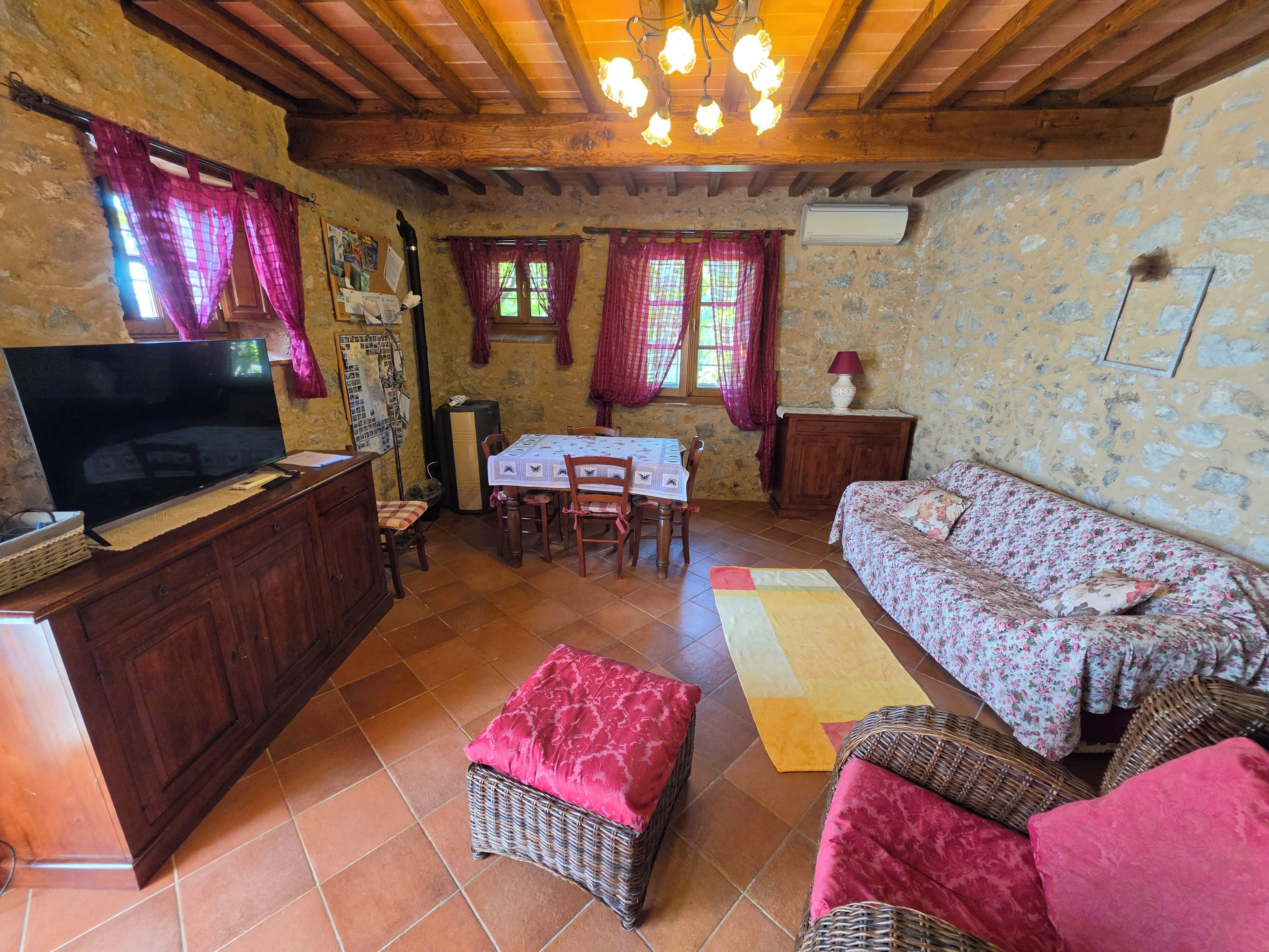 Un salon chaleureux avec un téléviseur, une table à manger, des meubles en osier et une cheminée.