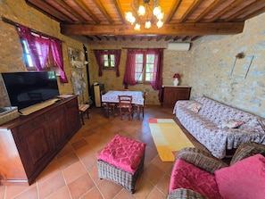 Uma sala de estar aconchegante com televisão, mesa de jantar, móveis de vime e lareira.
